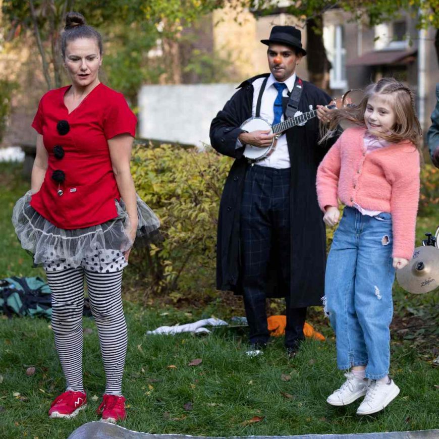 Girl dancing with performing clowns