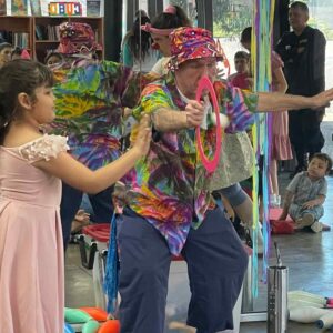 A girl demonstrates clown energy in action by throwing her egg through a hoop and into a basket.