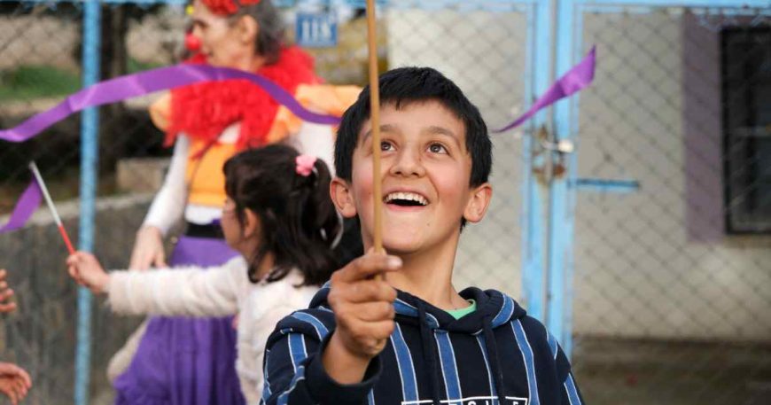 A boy survivor of the Turkey earthquake has a great time balancing a plate at a clown show.