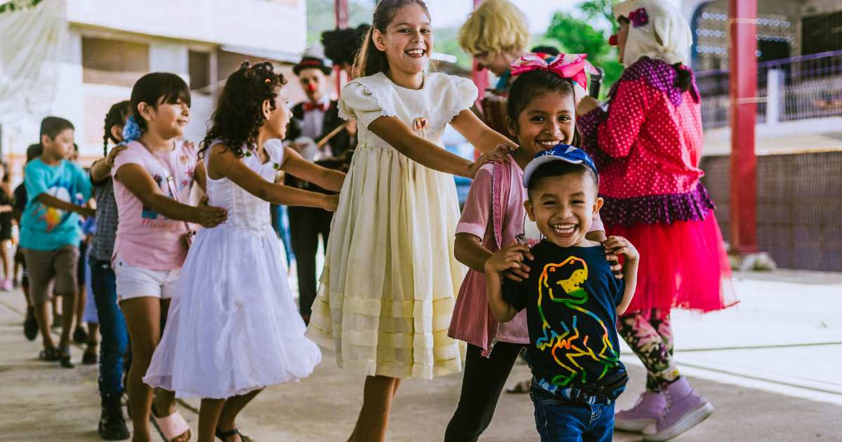 a small boy leads a train of 3 older girls in at a clown show in Acapulco, MX.