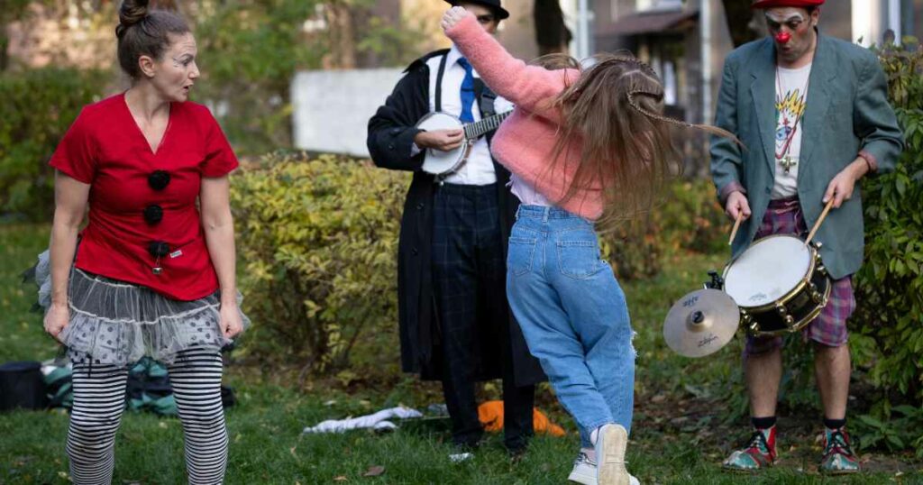 A Ukrainian refugee girl leaps into the air at a clown show in Poland.