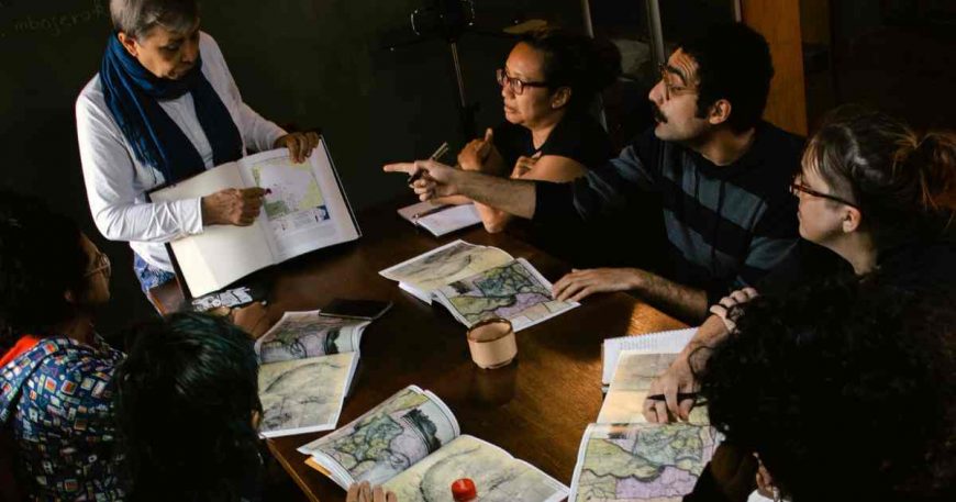 CWB at desk learning about Guarani ancestral lands and resettlement history from an Indigenous teacher