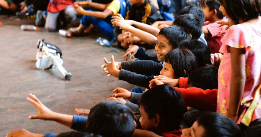 Kids from the Guarani community sit and watch a clown show