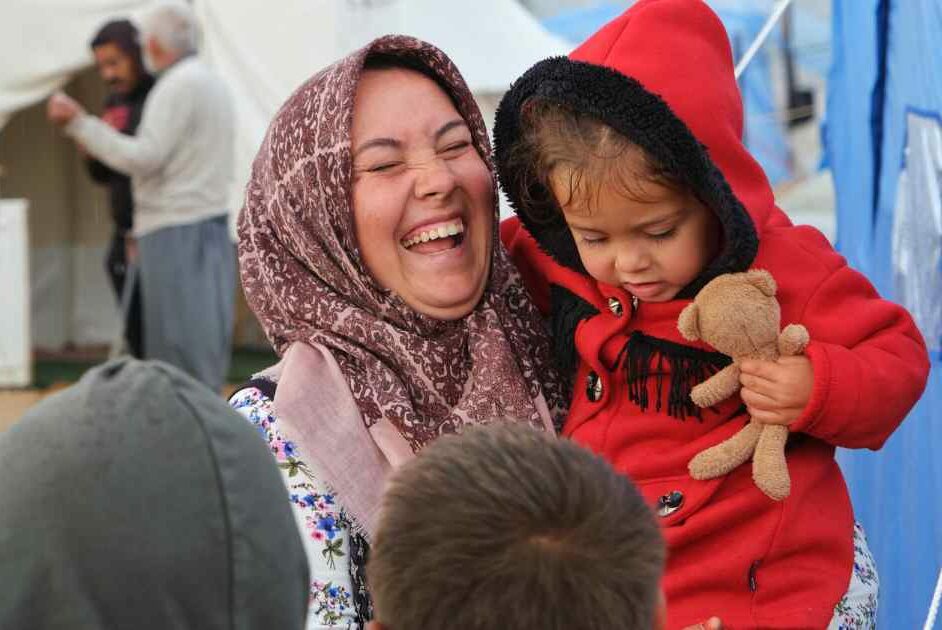 A Turkish woman laughs as she holds her baby.