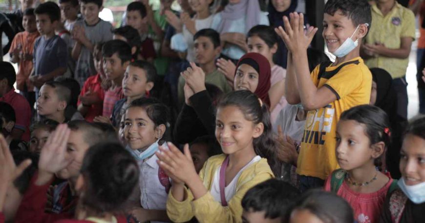 A girl in yellow claps at a clown show in Lebanon