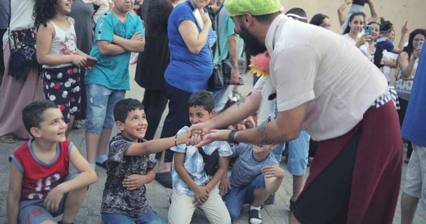 Clown holding outreached hand of child