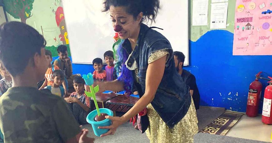 Clown presenting plastic plant to child