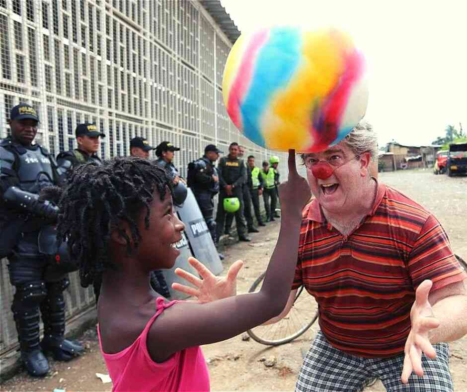 Clown with girl whose smiling as she spins a ball on her finger