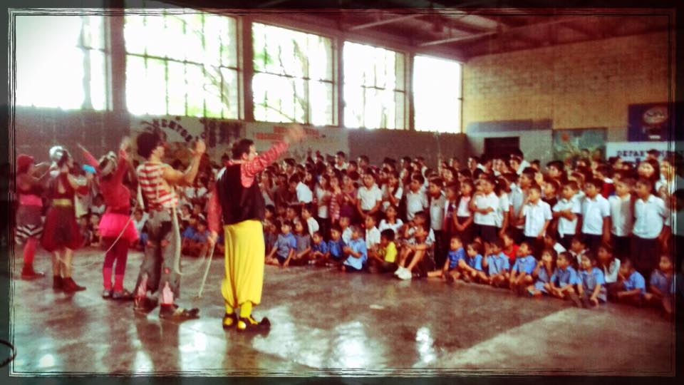 clowns perform in an auditorium full of children